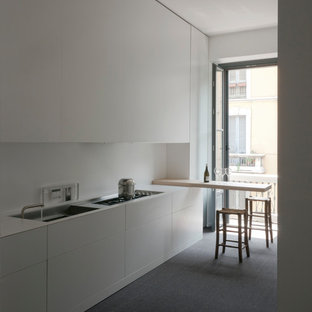 Foto di una cucina lineare moderna chiusa e di medie dimensioni con lavello a vasca singola, ante lisce, ante bianche, top in quarzo composito, paraspruzzi bianco, elettrodomestici da incasso, moquette, penisola e pavimento grigio