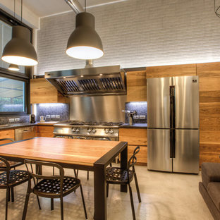 Foto di una grande cucina industriale con lavello a doppia vasca, ante lisce, ante in legno chiaro, top in granito, elettrodomestici in acciaio inossidabile e pavimento grigio