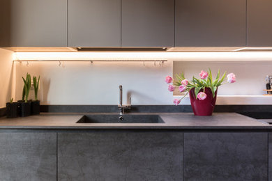 Idee per una cucina parallela minimal chiusa e di medie dimensioni con ante a filo, ante grigie, lavello integrato, top piastrellato, parquet chiaro e pavimento marrone