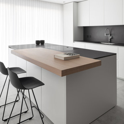 Kitchen - mid-sized contemporary galley gray floor kitchen idea in Venice with an undermount sink, flat-panel cabinets, white cabinets, black backsplash, an island and black countertops