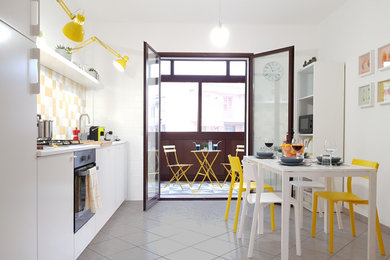 Esempio di una cucina design con ante lisce, ante bianche, paraspruzzi giallo, elettrodomestici in acciaio inossidabile, nessuna isola, pavimento grigio e top bianco