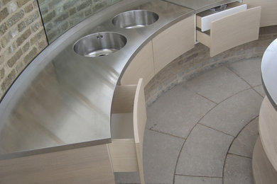 Idee per una cucina minimal con ante in legno chiaro, top in acciaio inossidabile, pavimento in pietra calcarea, pavimento grigio e top grigio