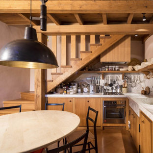 Esempio di una cucina mediterranea con lavello integrato, ante lisce, ante in legno scuro, paraspruzzi bianco, paraspruzzi in lastra di pietra, elettrodomestici in acciaio inossidabile, pavimento in cemento, nessuna isola, pavimento marrone e top bianco