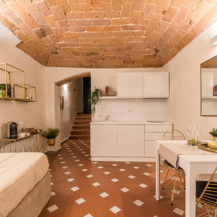 Esempio di una piccola cucina mediterranea con lavello da incasso, ante lisce, ante bianche, paraspruzzi bianco, nessuna isola, pavimento marrone e top bianco