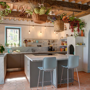 Idee per un cucina con isola centrale mediterraneo chiuso con ante lisce, ante grigie, paraspruzzi grigio, paraspruzzi in lastra di pietra, pavimento in terracotta, pavimento arancione, top grigio e travi a vista