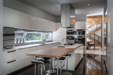 This is an example of an expansive contemporary kitchen/diner in Miami with white cabinets, stainless steel appliances and an island.