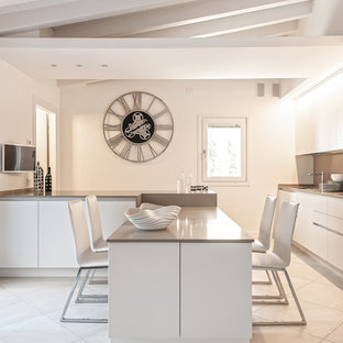 Idee per una grande cucina minimal con ante lisce, ante bianche, top in superficie solida, paraspruzzi beige e penisola