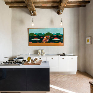 Ejemplo de cocina minimalista con fregadero encastrado, armarios con paneles lisos, puertas de armario blancas, suelo de ladrillo y una isla