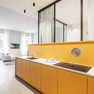 Foto di una cucina minimalista con lavello sottopiano, ante lisce, ante gialle, paraspruzzi giallo, parquet chiaro, top bianco, nessuna isola e pavimento beige