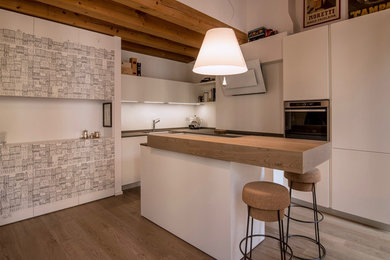 Ispirazione per una cucina minimalista di medie dimensioni con ante lisce, ante bianche, paraspruzzi bianco, elettrodomestici in acciaio inossidabile, pavimento in legno massello medio e pavimento marrone