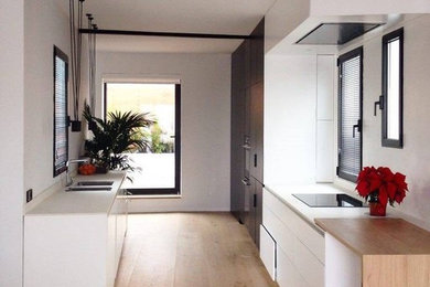 Foto de cocina contemporánea grande abierta con fregadero de doble seno, armarios con paneles lisos, encimera de cuarzo compacto, electrodomésticos negros y encimeras blancas