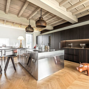 Immagine di una cucina industriale con ante in acciaio inossidabile, lavello integrato, ante lisce, top in acciaio inossidabile, paraspruzzi nero, elettrodomestici in acciaio inossidabile, parquet chiaro, pavimento beige e top grigio