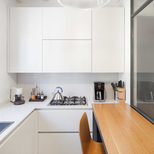 Foto di una cucina ad U minimal chiusa con lavello da incasso, ante lisce, ante bianche, penisola e pavimento bianco