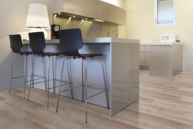 Immagine di una piccola cucina minimalista con ante lisce, ante grigie, top in laminato, elettrodomestici in acciaio inossidabile, pavimento in vinile e penisola