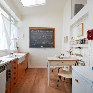Ispirazione per una cucina bohémian con ante in legno scuro, elettrodomestici in acciaio inossidabile, pavimento in legno massello medio, nessuna isola, lavello stile country, ante lisce, pavimento marrone e top bianco