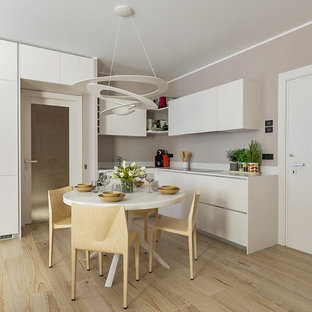 Immagine di una cucina design di medie dimensioni con ante lisce, ante bianche, top in superficie solida, elettrodomestici in acciaio inossidabile, parquet chiaro, nessuna isola, top bianco e pavimento beige
