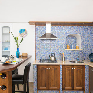Esempio di una cucina a L mediterranea con lavello a vasca singola, ante con bugna sagomata, ante in legno scuro, paraspruzzi multicolore, elettrodomestici in acciaio inossidabile, penisola e top beige