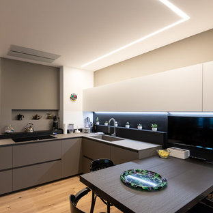 Idee per una cucina design con lavello a vasca singola, ante lisce, ante grigie, paraspruzzi nero, parquet chiaro e top grigio