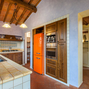 Esempio di una cucina ad U mediterranea con lavello da incasso, ante con bugna sagomata, ante in legno bruno, paraspruzzi multicolore, elettrodomestici colorati, pavimento in mattoni, nessuna isola, pavimento rosso e top giallo