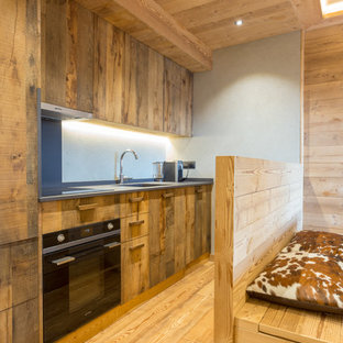 Idee per una cucina stile rurale con pavimento in legno massello medio, nessuna isola, ante lisce, ante in legno bruno, pavimento marrone e top grigio
