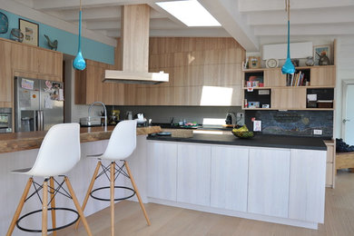 Ispirazione per una cucina moderna con ante in legno chiaro, elettrodomestici in acciaio inossidabile e parquet chiaro