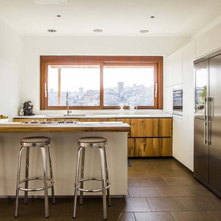 Esempio di una cucina ad U contemporanea con ante lisce, elettrodomestici in acciaio inossidabile, pavimento grigio, ante in legno scuro, top in legno, penisola e top marrone