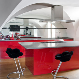 Ispirazione per un cucina con isola centrale contemporaneo con lavello sottopiano, ante lisce, ante rosse, paraspruzzi a specchio, parquet chiaro e top grigio