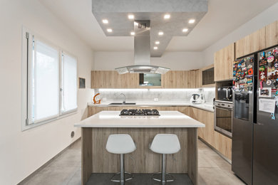 Diseño de cocina minimalista extra grande con puertas de armario de madera clara, encimera de acrílico, electrodomésticos de acero inoxidable, suelo de baldosas de porcelana, una isla y suelo gris