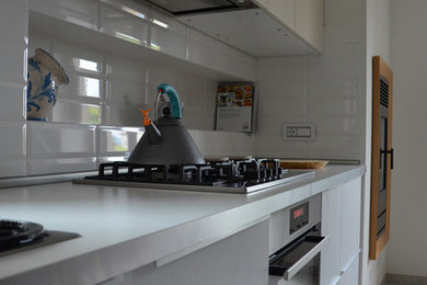 Idee per una cucina design di medie dimensioni con lavello da incasso, ante bianche, top in laminato, elettrodomestici in acciaio inossidabile, pavimento in gres porcellanato e pavimento grigio
