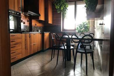ミラノにある低価格の中くらいなコンテンポラリースタイルのおしゃれなキッチン (ドロップインシンク、中間色木目調キャビネット、木材カウンター、グレーのキッチンパネル、大理石のキッチンパネル、黒い調理設備、グレーのキッチンカウンター) の写真