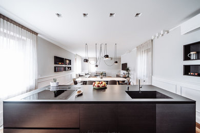 This is an example of a large contemporary open plan kitchen in Turin with a submerged sink, flat-panel cabinets, stainless steel cabinets, stainless steel worktops, an island and black worktops.