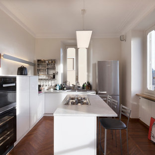 Immagine di una cucina a L minimal di medie dimensioni con ante lisce, ante bianche, top in marmo, isola, lavello a doppia vasca, elettrodomestici neri e pavimento in legno massello medio