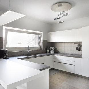 Ispirazione per una cucina ad U moderna con lavello a doppia vasca, ante lisce, ante bianche, paraspruzzi grigio, elettrodomestici in acciaio inossidabile, parquet scuro, penisola, pavimento marrone e top grigio