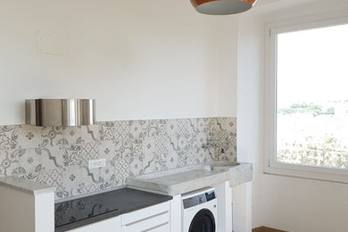 Immagine di una cucina minimal di medie dimensioni con ante lisce, ante bianche, top in laminato, paraspruzzi multicolore, paraspruzzi in gres porcellanato, pavimento in laminato e top nero