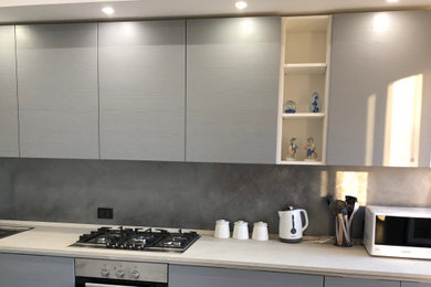 Idee per una cucina lineare design di medie dimensioni con lavello da incasso, top in laminato, elettrodomestici in acciaio inossidabile, pavimento in gres porcellanato, pavimento beige e top bianco