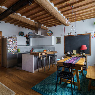 Foto di un'ampia cucina bohémian con pavimento marrone, ante lisce, ante bianche, elettrodomestici in acciaio inossidabile, pavimento in legno massello medio, penisola e top grigio