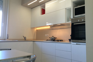 Immagine di una cucina a L scandinava chiusa e di medie dimensioni con lavello da incasso, ante bianche, elettrodomestici in acciaio inossidabile, pavimento in gres porcellanato e pavimento beige