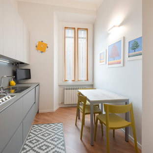 Foto di una cucina lineare contemporanea con ante lisce, ante grigie, pavimento in legno massello medio, nessuna isola, pavimento marrone e top grigio