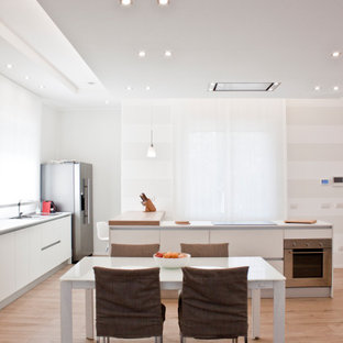 Idee per una cucina contemporanea di medie dimensioni con lavello da incasso, ante lisce, ante bianche, elettrodomestici in acciaio inossidabile, pavimento in legno massello medio, pavimento beige e top bianco