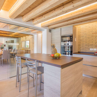 Idee per una grande cucina ad ambiente unico mediterranea con isola, ante lisce, ante in legno chiaro, paraspruzzi in mattoni, parquet chiaro, pavimento beige e top marrone