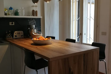 Cette photo montre une cuisine américaine tendance en L de taille moyenne avec un évier encastré, un placard à porte plane, des portes de placard blanches, un plan de travail en quartz modifié, une crédence grise, parquet clair et un plan de travail gris.