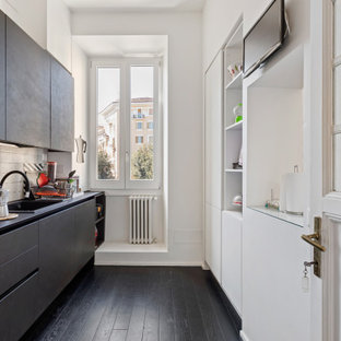 Ispirazione per una cucina parallela minimal chiusa e di medie dimensioni con lavello da incasso, ante lisce, ante nere, paraspruzzi grigio, paraspruzzi con piastrelle di cemento, elettrodomestici da incasso, nessuna isola, pavimento nero e top nero