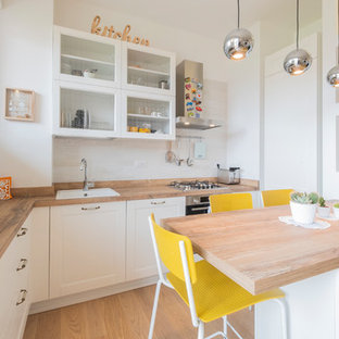 Ispirazione per una cucina a L nordica con lavello da incasso, ante con bugna sagomata, ante bianche, top in legno, paraspruzzi bianco, pavimento in legno massello medio, penisola, pavimento marrone e top marrone