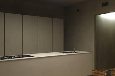 Foto de cocina lineal actual de tamaño medio abierta con armarios con rebordes decorativos, puertas de armario grises, encimera de acrílico, suelo de madera pintada, una isla y encimeras grises