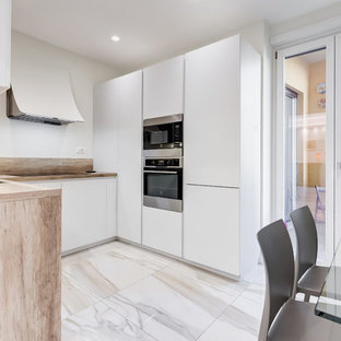 Foto di una cucina contemporanea con lavello sottopiano, ante lisce, ante bianche, top in legno, paraspruzzi marrone, paraspruzzi in legno, elettrodomestici in acciaio inossidabile, nessuna isola, pavimento bianco e top marrone