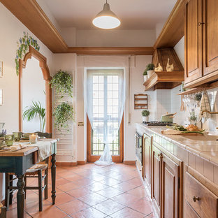 Ispirazione per una cucina mediterranea con lavello da incasso, ante con bugna sagomata, ante in legno scuro, paraspruzzi bianco, elettrodomestici da incasso, pavimento in terracotta, nessuna isola, pavimento arancione e top beige