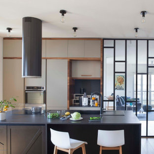 Foto di una cucina contemporanea chiusa e di medie dimensioni con lavello da incasso, ante lisce, ante grigie, elettrodomestici da incasso, pavimento marrone e top nero