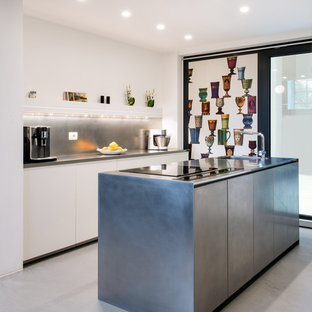 Ispirazione per una cucina minimal di medie dimensioni con lavello integrato, ante lisce, ante in acciaio inossidabile, top in acciaio inossidabile, elettrodomestici in acciaio inossidabile, pavimento in cemento, pavimento grigio, paraspruzzi grigio e top grigio