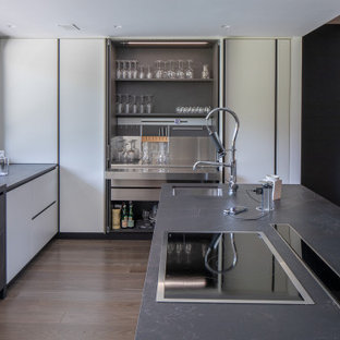 Idee per una cucina contemporanea con lavello integrato, ante lisce, ante bianche, parquet scuro, isola, pavimento marrone e top grigio