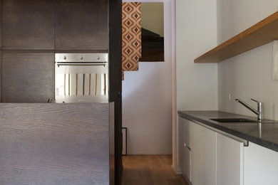 フィレンツェにあるお手頃価格の広いコンテンポラリースタイルのおしゃれなキッチン (シングルシンク、フラットパネル扉のキャビネット、濃色木目調キャビネット、シルバーの調理設備、無垢フローリング) の写真